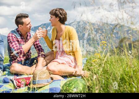 Coppia che ha un picnic su un prato in montagna clidking occhiali, Achenkirch, Austria Foto Stock