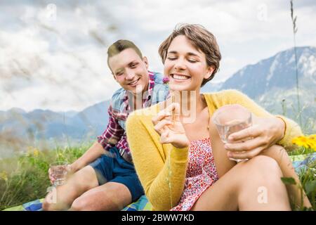 Coppia che ha un picnic su un prato in montagna, Achenkirch, Austria Foto Stock