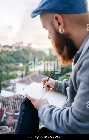 Uomo al punto di osservazione che traccia un disegno dell'Alhambra, Granada, Spagna Foto Stock