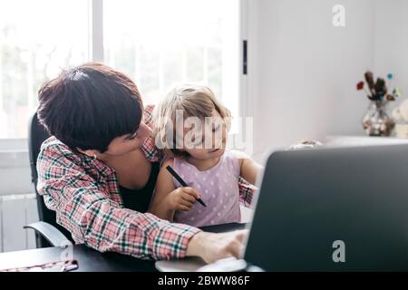 Madre che lavora a casa con sua figlia Foto Stock