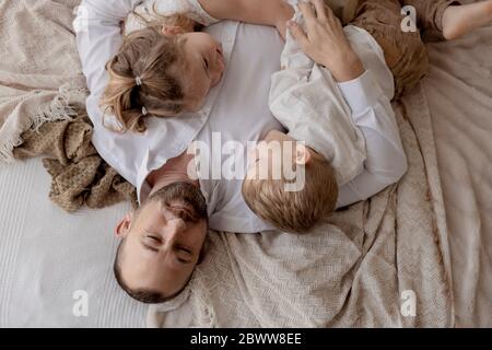 Ritratto di padre che si stendeva a letto con i suoi due figli che si rilassano Foto Stock