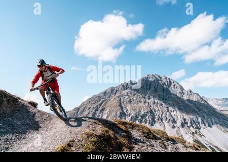 Uomo in mountain bike, Valle Munestertal, Grigioni, Svizzera Foto Stock