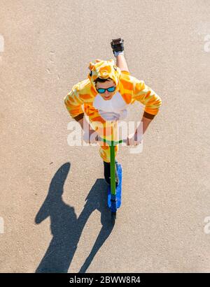 Giovane uomo che indossa costume da giraffa su scooter dall'alto Foto Stock