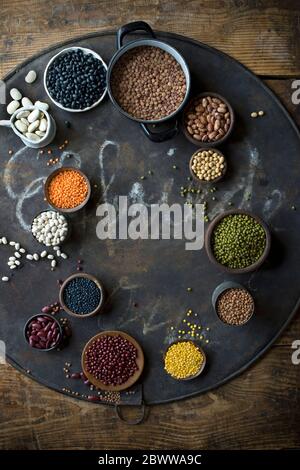 Ciotole con vari fagioli e lenticchie su teglia rustica Foto Stock