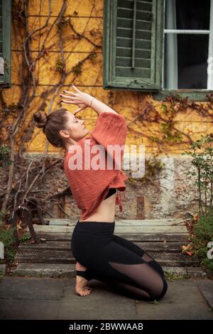 Donna che pratica yoga di fronte al muro Foto Stock