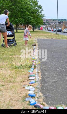 Brighton UK 3 giugno 2020 - Isabella Lloyd, di tre anni, aggiunge il suo ciottolo dipinto al serpente di roccia, creato con centinaia di ciottoli dipinti dai bambini nel parco di Lockwood Woodingdean vicino a Brighton . I serpenti di roccia sono comparsi intorno al paese durante la crisi pandemica del coronavirus COVID-19 alcuni ringraziano l'NHS e i lavoratori chiave. Credit: Simon Dack / Alamy Live News Foto Stock