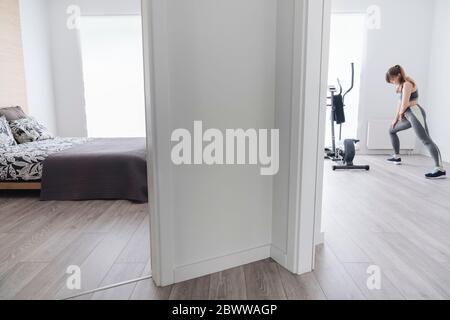 Donna che esegue esercizi di stretching prima di un allenamento a casa Foto Stock