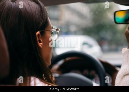 Primo piano di una donna che guida un'auto convertibile in città Foto Stock