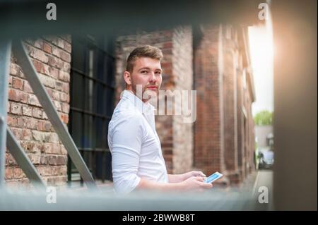 Giovane uomo d'affari che usa la tavoletta in un edificio di mattoni Foto Stock