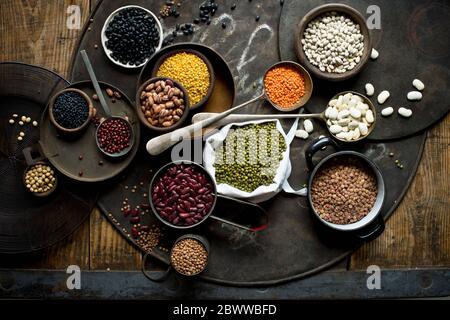 Ciotole con vari fagioli e lenticchie su teglia rustica Foto Stock