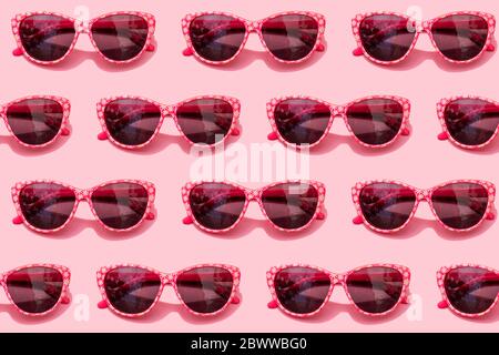 Modello di occhiali da sole retrò rosa su sfondo rosa pastello Foto Stock