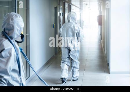 Personale addetto alla pulizia che desinfetta l'ospedale da virus scandalosi, indossando indumenti protettivi Foto Stock