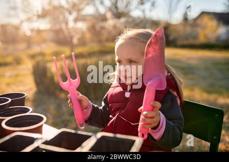 Ritratto di ragazza che tiene gli attrezzi di giardinaggio Foto Stock