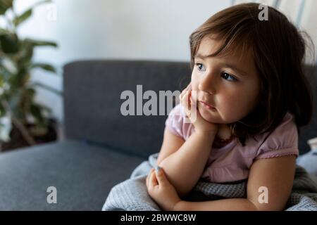 Ritratto di ragazza seduta sul divano a casa Foto Stock