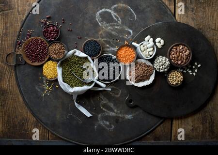 Ciotole con vari fagioli e lenticchie su teglia rustica Foto Stock