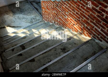 Vista dall'alto della scala in cemento con parete in mattoni e luce a terra. Foto Stock