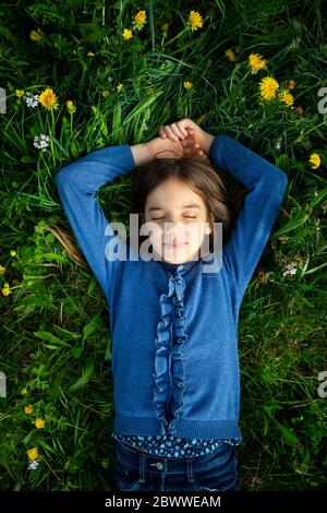 Ritratto di ragazza con gli occhi chiusi rilassandosi su un prato in primavera Foto Stock