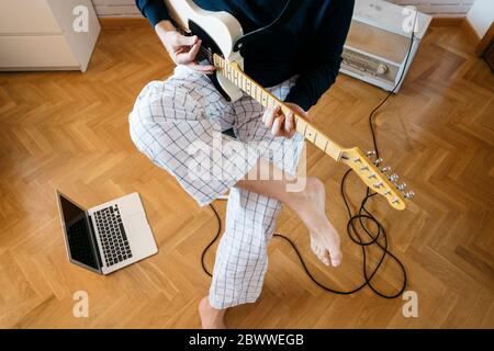 Vista di ritaglio di un uomo che suona la chitarra elettrica a casa Foto Stock