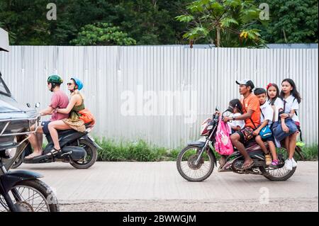 Le motociclette a volte con intere famiglie si fanno strada attraverso le strade polverose di Coron Town proprio sull'isola di Coron, Palawan, le Filippine. Foto Stock