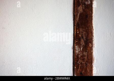 Vecchio palo di legno all'interno muro di cemento bianco sfondo. Foto Stock