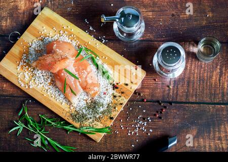 Pollo a scatti si trova su un tavolo con spezie e sale marino. Rosmarino, cardamomo, pepe. Foto Stock