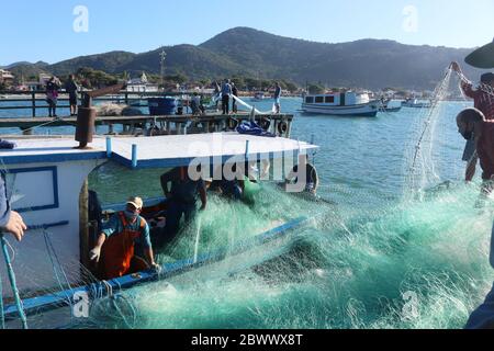 Rete da pesca spedita per una nuova giornata lavorativa. Dopo aver scaricato i triglie pescati, i pescatori rimettono la rete sulla barca Foto Stock