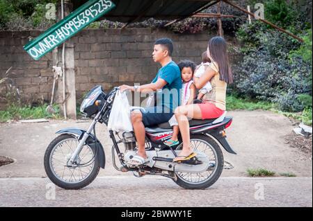 Le motociclette a volte con intere famiglie si fanno strada attraverso le strade polverose di Coron Town proprio sull'isola di Coron, Palawan, le Filippine. Foto Stock