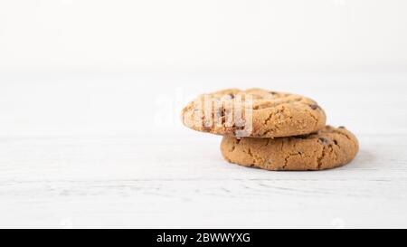 Due biscotti con gocce di cioccolato su tavolo di legno bianco. Biscotti al cioccolato. Porzione di biscotti mattutini. Spazio di testo Foto Stock