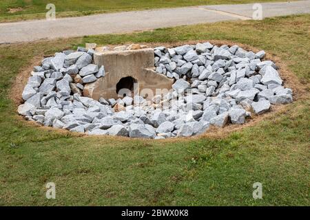 Parete di fondo in cemento fuso invecchiato per deflusso di acque piovane circondata da nuove rocce, sicurezza ambientale, spazio copia erba verde, aspetto orizzontale Foto Stock