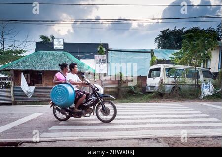 Le motociclette a volte con intere famiglie si fanno strada attraverso le strade polverose di Coron Town proprio sull'isola di Coron, Palawan, le Filippine. Foto Stock