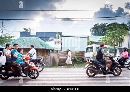 Le motociclette a volte con intere famiglie si fanno strada attraverso le strade polverose di Coron Town proprio sull'isola di Coron, Palawan, le Filippine. Foto Stock