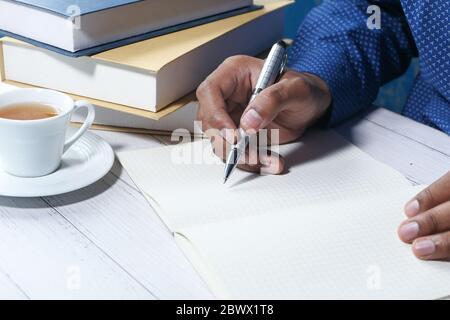 Voce maschile la scrittura a mano in notebook con penna Foto Stock