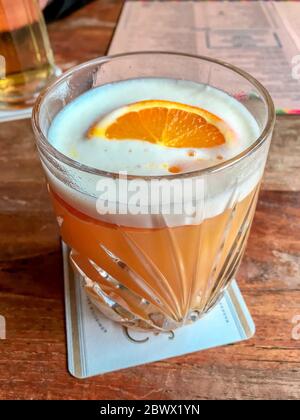 Una tazza con una bevanda al pisco acido arancione Foto Stock