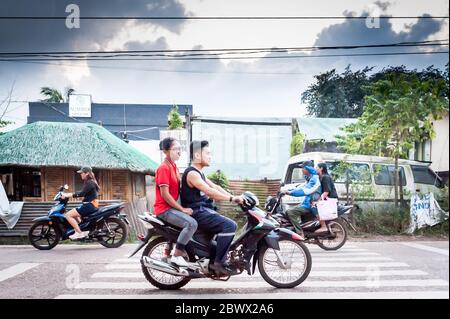 Le motociclette a volte con intere famiglie si fanno strada attraverso le strade polverose di Coron Town proprio sull'isola di Coron, Palawan, le Filippine. Foto Stock