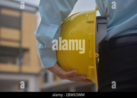 Engineering Holding Yellow hard Hat sicurezza lavoro costruzione architettura, controllo di gestione del progetto Foto Stock