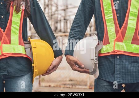 Ingegneria delle costruzioni due persone che tengono il casco elmetto di sicurezza lavori di costruzione industriale Foto Stock