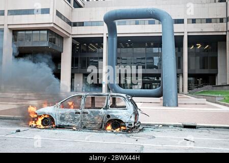 Un'auto brucia su Ontario Street fuori dal Cleveland Police Department nel centro di Cleveland, Ohio, USA durante le proteste contro l'uccisione della polizia di George Floyd. L'entrata di Ontario Street e' fiancheggiata dalla scultura di Isamu Noguchi chiamata 'Portal, una scultura alta 36 piedi progettata per riflettere 'una porta alla speranza o alla disperazione'. Foto Stock