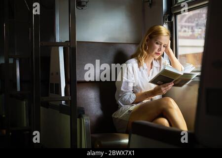 Una donna che legge un libro su un treno Foto Stock
