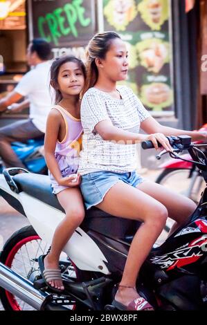 Le motociclette a volte con intere famiglie si fanno strada attraverso le strade polverose di Coron Town proprio sull'isola di Coron, Palawan, le Filippine. Foto Stock