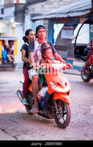 Le motociclette a volte con intere famiglie si fanno strada attraverso le strade polverose di Coron Town proprio sull'isola di Coron, Palawan, le Filippine. Foto Stock