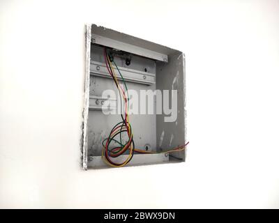 scatola di derivazione in acciaio elettrico non rifinita su parete in mattoni bianchi. Lavori di installazione elettrica domestica, riparazione cablaggio domestico. Aggiornare il sistema di alimentazione in Th Foto Stock