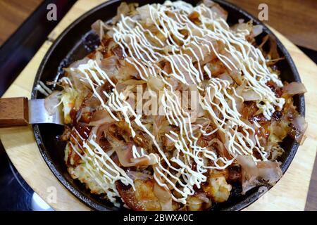 Okonomiyaki in piatto caldo che è una famosa ricetta giapponese. Foto Stock