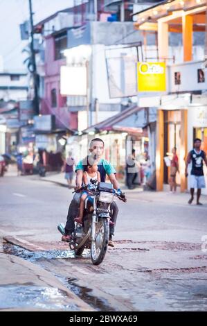 Le motociclette a volte con intere famiglie si fanno strada attraverso le strade polverose di Coron Town proprio sull'isola di Coron, Palawan, le Filippine. Foto Stock