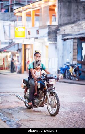 Le motociclette a volte con intere famiglie si fanno strada attraverso le strade polverose di Coron Town proprio sull'isola di Coron, Palawan, le Filippine. Foto Stock