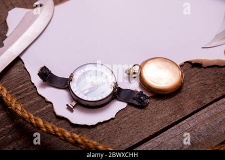 Carta vecchia con bussola, coltello e corda su tavola di legno d'epoca. Vista dall'alto dello spazio vuoto per il testo. Foto Stock