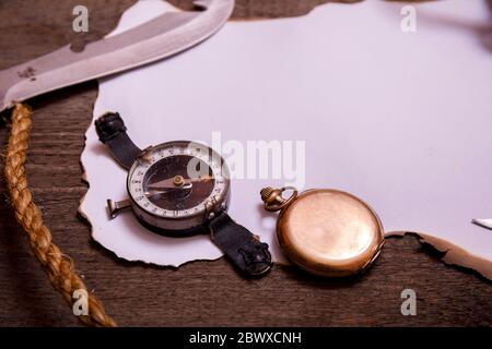 Carta vecchia con bussola, coltello e corda su tavola di legno d'epoca. Vista dall'alto dello spazio vuoto per il testo. Foto Stock