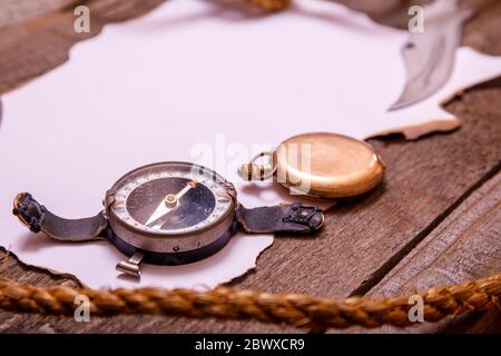 Carta vecchia con bussola, coltello e corda su tavola di legno d'epoca. Vista dall'alto dello spazio vuoto per il testo. Foto Stock