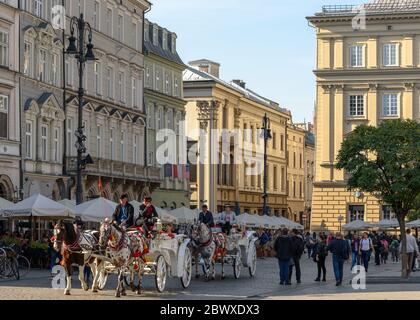 Cavalli e carrozze sulla Piazza della Città Vecchia di Cracovia Foto Stock