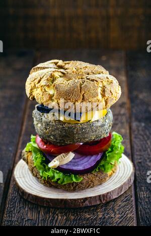 pasto vegano, hamburger senza carne, senza glutine, fatto con verdure e proteine diverse. Pane marrone su hamburger gourmet, sfondo rustico. Foto Stock