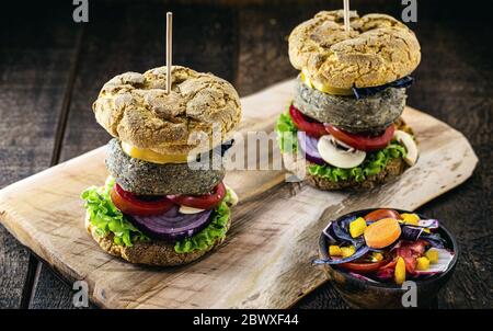 Hamburger gustoso e vegano di riso e verdure, su rustico sfondo di legno. Alimenti vegani senza carne o prodotti animali. Foto Stock